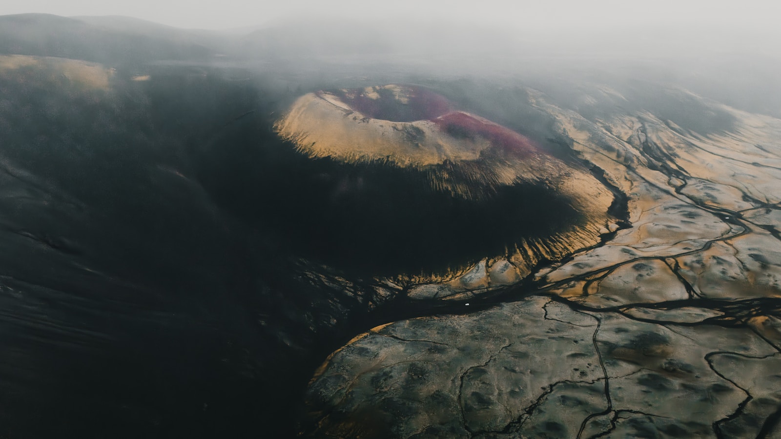 Aerial view of a volcanic crater with colorful mineral deposits